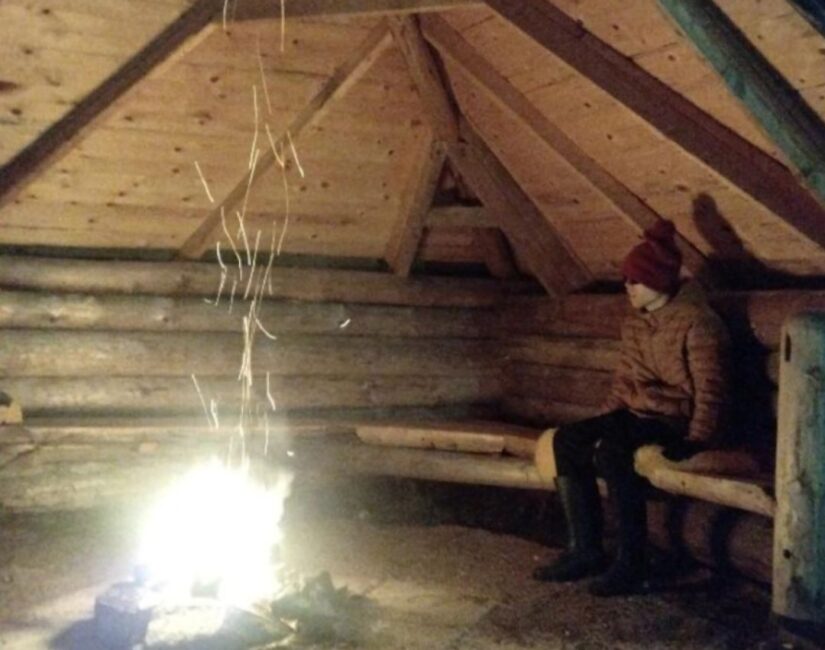 Poika istuu laavulla ja katselee nuotiota