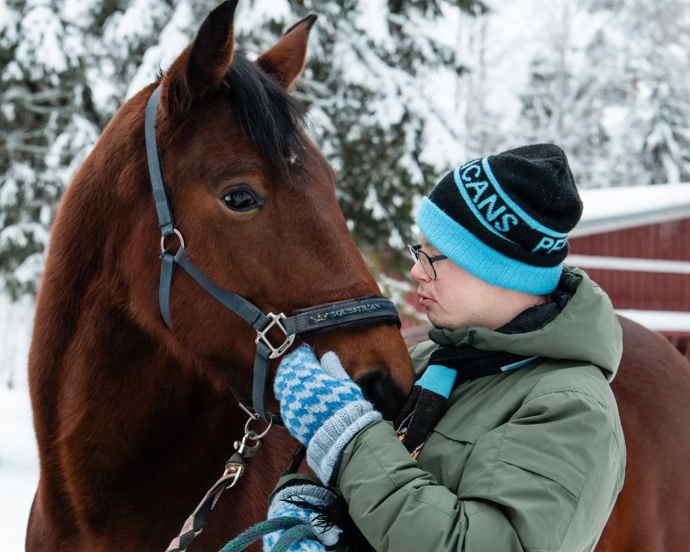 Kehitysvammainen poika silittelee hevosen turpaa
