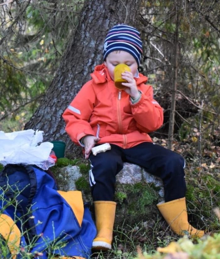 Pikkupoika istuu kivellä ja syö eväitä