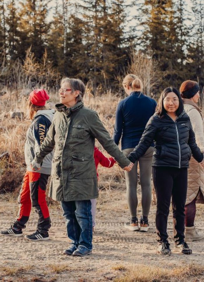 Kuusi ihmistä seisovat ympyrässä ja pitävät toisiaan kädestä